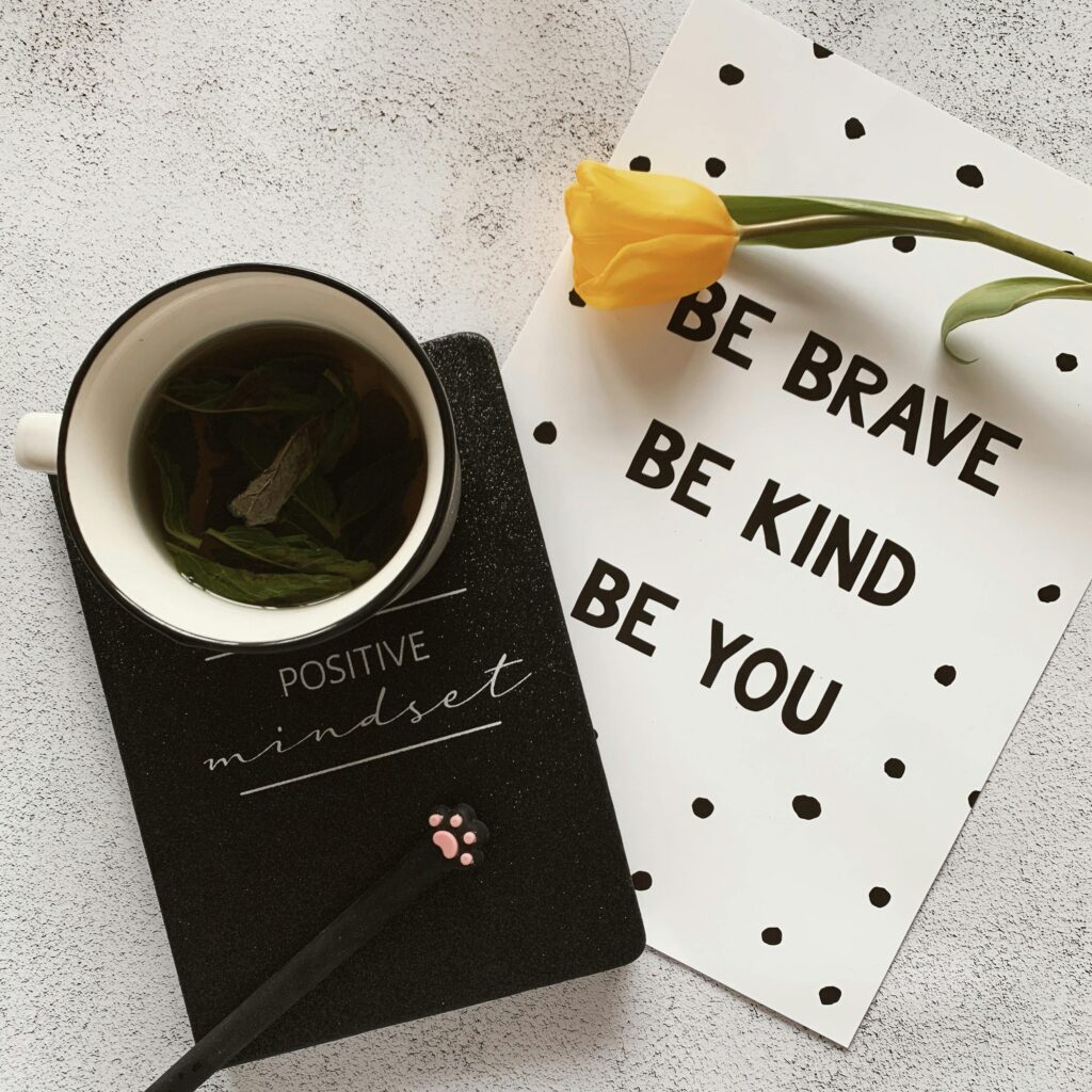 Top view of cup of hot natural tea on notepad placed near tulip on card with wishes